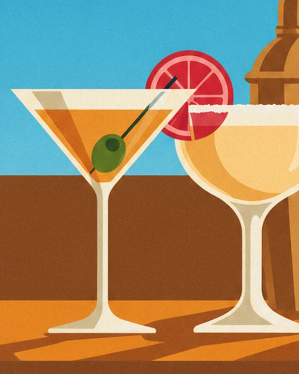 A martini with a green olive and a sugar-rimmed coupe on the wooden counter