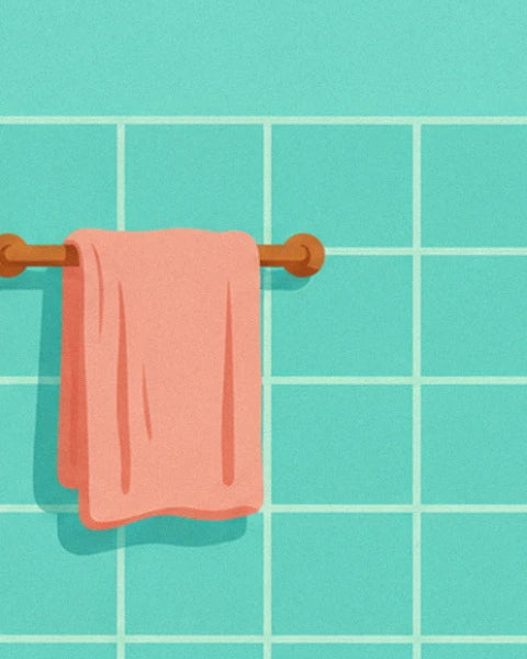 Pink towel folded over a brass rail against the turquoise tiled wall