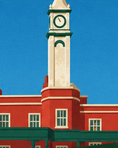 Der Uhrturm des Clubhauses mit roter Fassade und grünen Gesimsen unter blauem Himmel