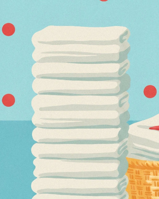 The tall pile of neatly folded white towels beside a wicker basket against a blue polka dot background