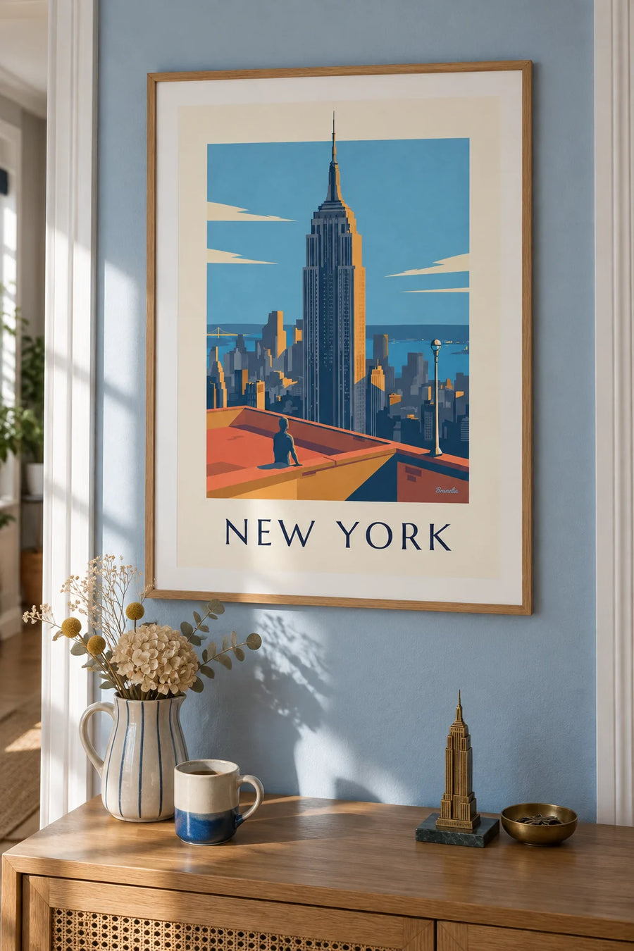 Poster of the Empire State Building towering over Manhattan in New York: framed on the wall